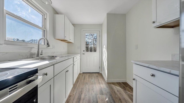 kitchen with plenty of natural light, white cabinets, and a sink