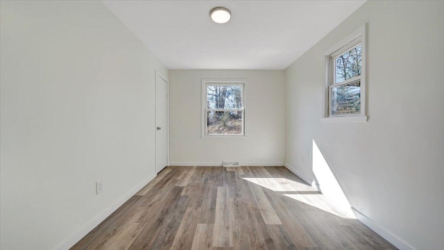 unfurnished room with visible vents, baseboards, and wood finished floors