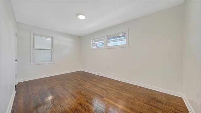 empty room with dark wood-style flooring and baseboards