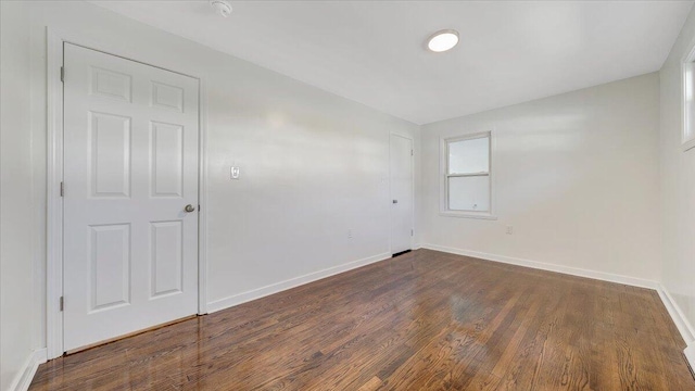 empty room with dark wood-style floors and baseboards