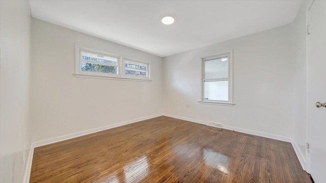 spare room featuring baseboards and dark wood-type flooring