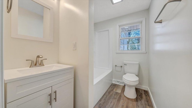 full bathroom with shower / washtub combination, toilet, vanity, wood finished floors, and baseboards