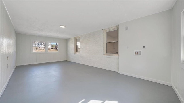 empty room with baseboards, brick wall, visible vents, and finished concrete floors