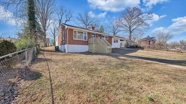 view of front of property featuring brick siding, a chimney, fence, central air condition unit, and a front yard