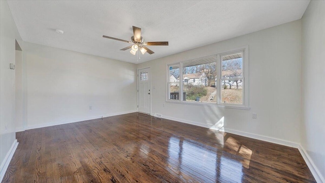 spare room with dark wood-type flooring, a textured ceiling, baseboards, and a ceiling fan