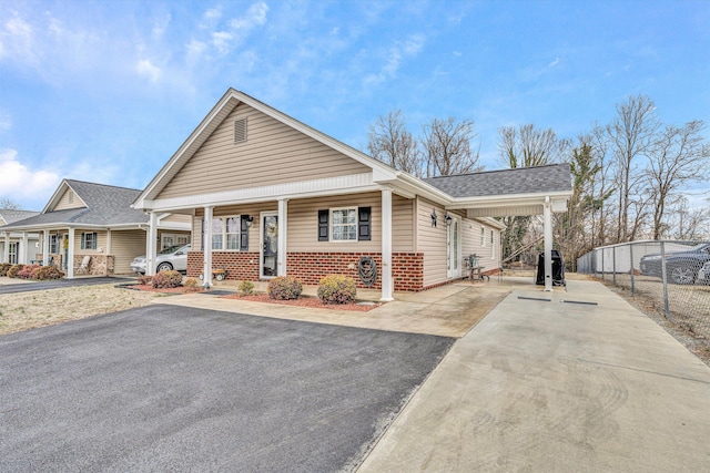 view of front of property with a shingled roof, brick siding, and fence