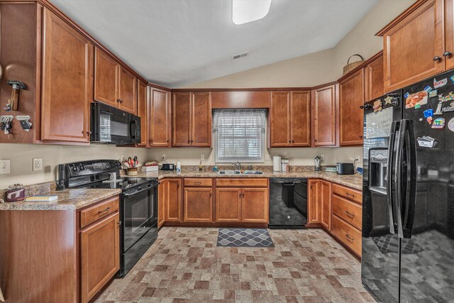 kitchen featuring lofted ceiling, black appliances, brown cabinetry, and a sink