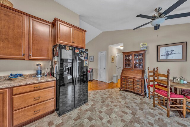 kitchen featuring brown cabinetry, lofted ceiling, black refrigerator with ice dispenser, and a ceiling fan