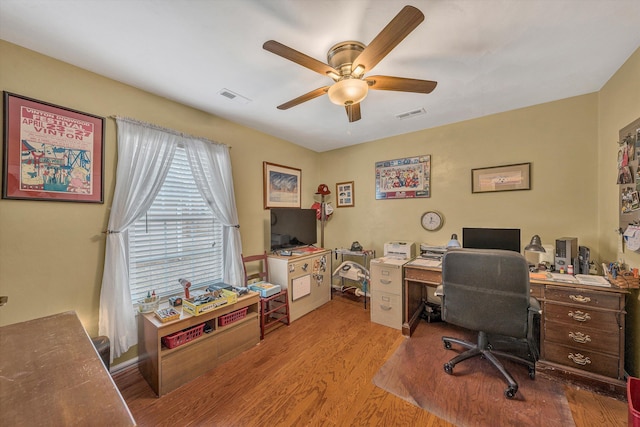 office space featuring a ceiling fan, visible vents, and wood finished floors