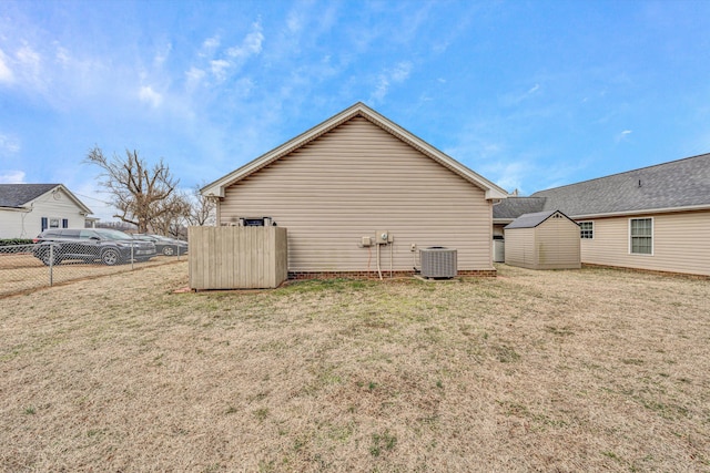 view of side of home with central AC unit, a yard, a storage unit, fence, and an outdoor structure