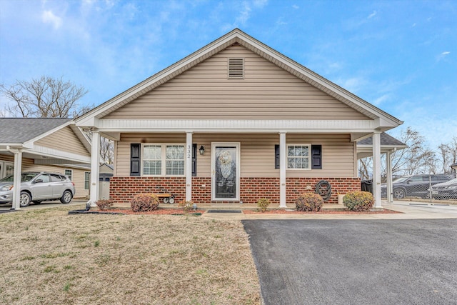 bungalow with covered porch, a front lawn, and brick siding