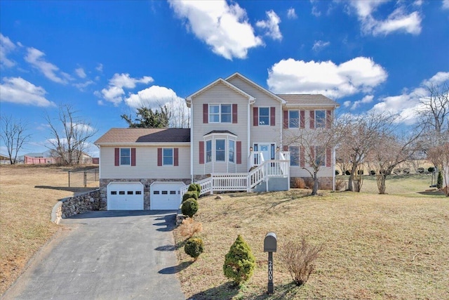 view of front of house featuring a front lawn, stone siding, driveway, and an attached garage