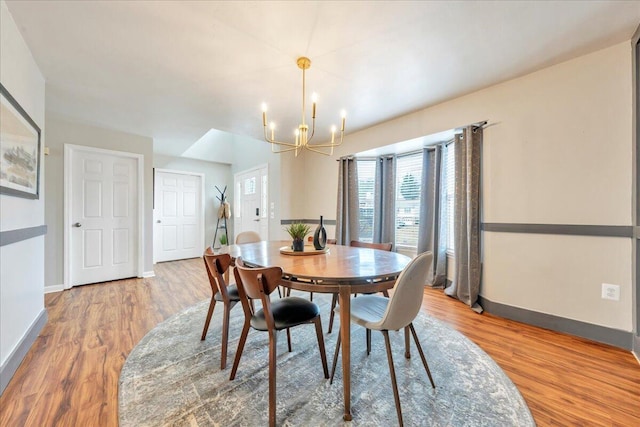 dining area with baseboards, an inviting chandelier, and wood finished floors