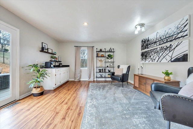 living area with recessed lighting, light wood-type flooring, visible vents, and baseboards