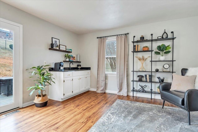 sitting room featuring light wood-style floors, visible vents, and baseboards