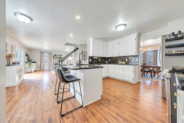 kitchen featuring dark countertops, white cabinetry, a breakfast bar area, and gas stove