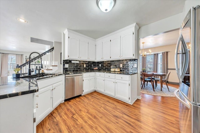 kitchen featuring dark countertops, light wood-type flooring, appliances with stainless steel finishes, and a sink