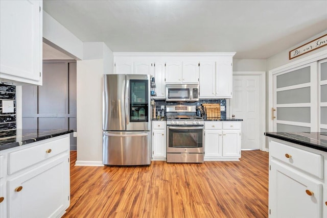 kitchen with appliances with stainless steel finishes, light wood-type flooring, and white cabinetry