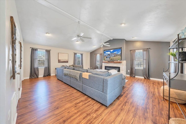 living area featuring lofted ceiling, a fireplace, wood finished floors, and baseboards