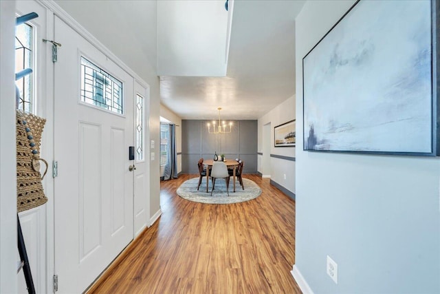 entryway featuring a healthy amount of sunlight, a notable chandelier, baseboards, and wood finished floors