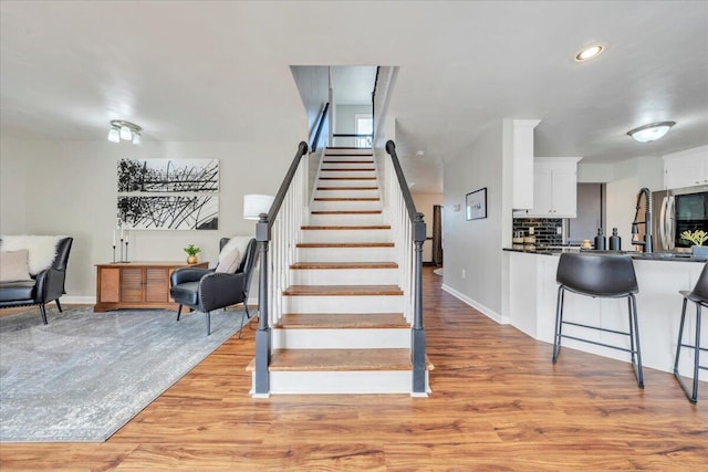 stairs featuring recessed lighting, wood finished floors, and baseboards