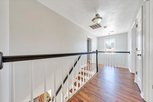 hall with wainscoting, visible vents, an upstairs landing, and wood finished floors