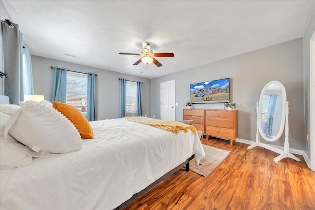 bedroom featuring a ceiling fan, baseboards, and wood finished floors