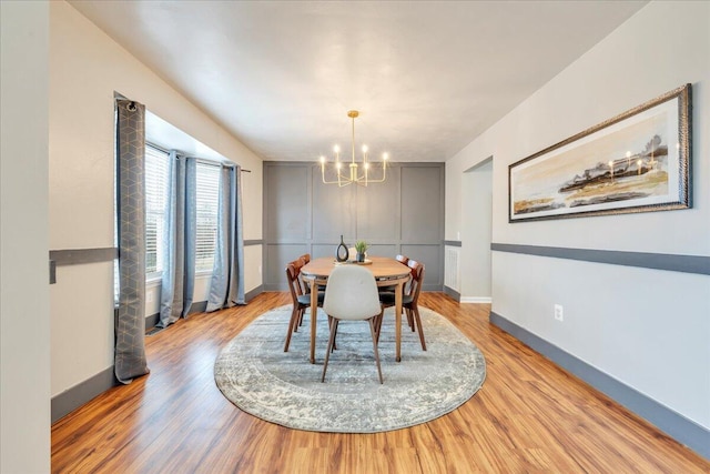 dining area with baseboards, light wood-style flooring, and an inviting chandelier