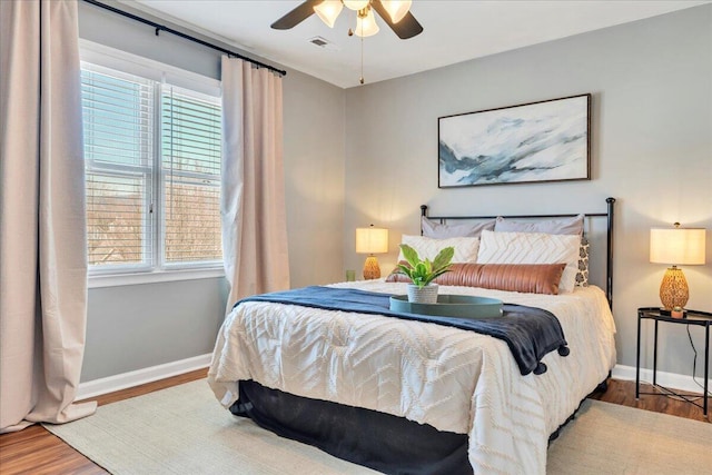 bedroom with baseboards, multiple windows, visible vents, and wood finished floors