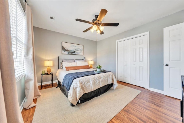 bedroom featuring baseboards, visible vents, ceiling fan, wood finished floors, and a closet