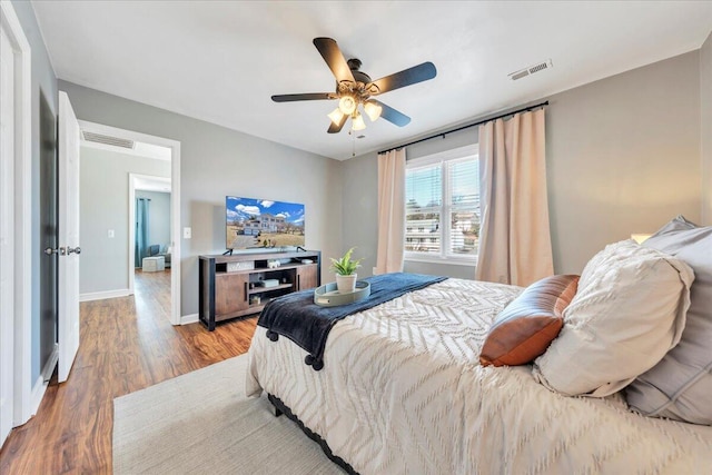 bedroom with baseboards, visible vents, ceiling fan, and wood finished floors