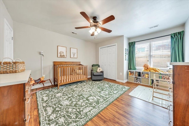 bedroom with visible vents, baseboards, ceiling fan, wood finished floors, and a closet