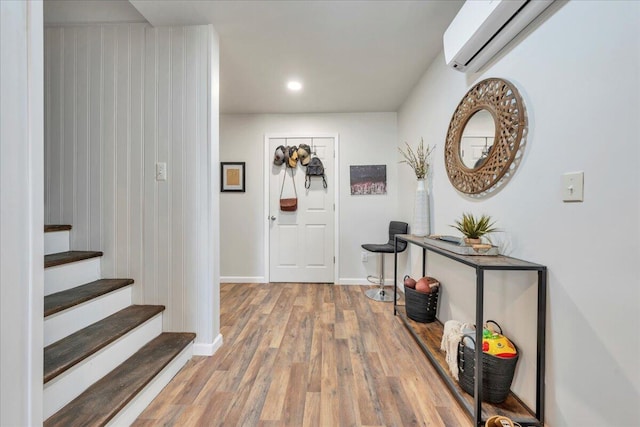 entrance foyer featuring baseboards, a wall unit AC, stairway, wood finished floors, and recessed lighting