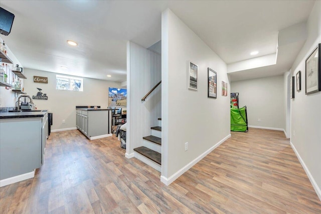 hallway featuring light wood-style floors, baseboards, and stairs