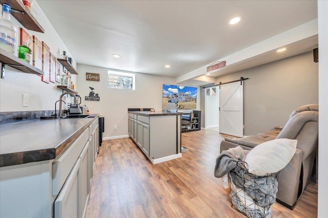 kitchen featuring dark countertops, light wood finished floors, a barn door, and open shelves