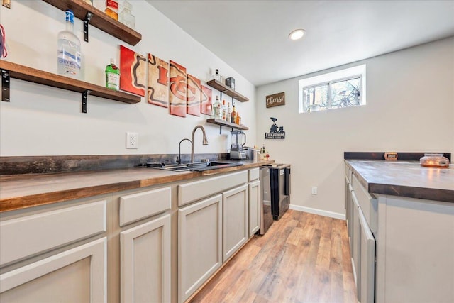 kitchen with light wood finished floors, baseboards, open shelves, a sink, and recessed lighting