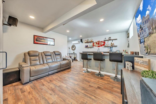 living room featuring an AC wall unit, wet bar, wood finished floors, and recessed lighting