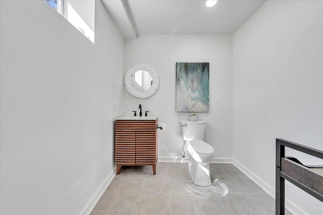 half bathroom featuring toilet, tile patterned floors, baseboards, and vanity