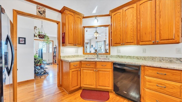 kitchen featuring a healthy amount of sunlight, black appliances, light wood-style flooring, and a sink