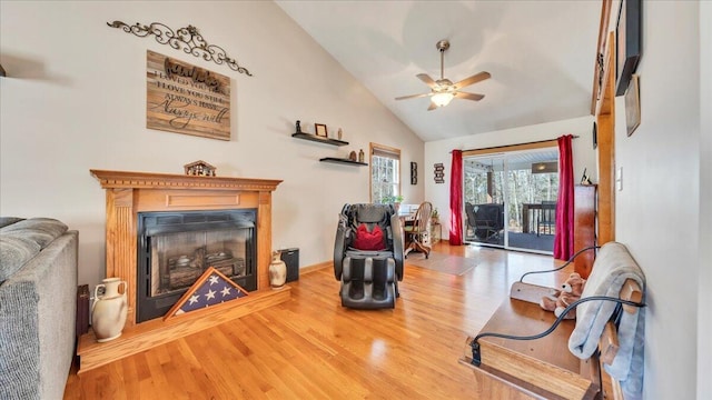 sitting room with a ceiling fan, vaulted ceiling, wood finished floors, and a glass covered fireplace