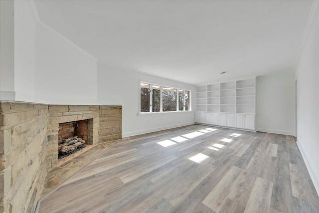 unfurnished living room featuring built in shelves, light wood-type flooring, and baseboards