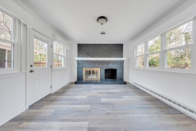 unfurnished living room featuring a baseboard heating unit, crown molding, and plenty of natural light