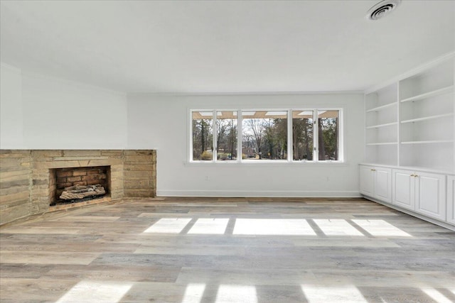 unfurnished living room with visible vents, baseboards, light wood-style floors, and a fireplace