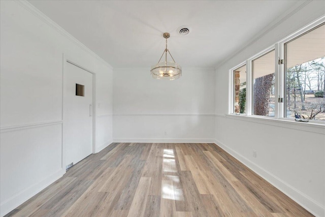 unfurnished room featuring crown molding, light wood-style floors, visible vents, and baseboards