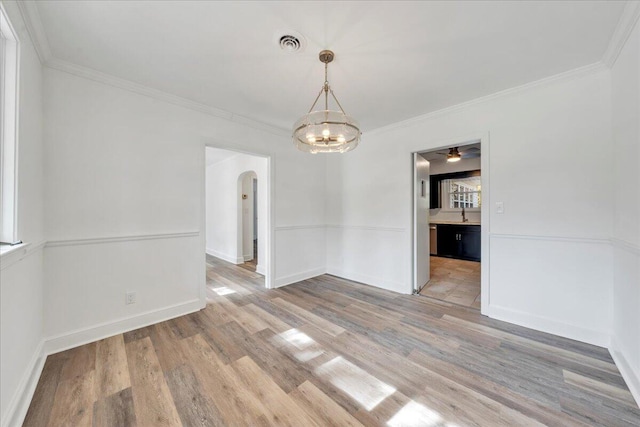 unfurnished dining area with light wood-type flooring, visible vents, arched walkways, crown molding, and baseboards