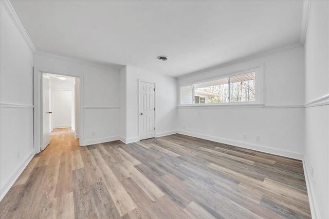 unfurnished bedroom with visible vents, baseboards, crown molding, and light wood finished floors