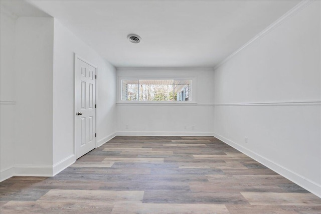 unfurnished room featuring crown molding, wood finished floors, visible vents, and baseboards