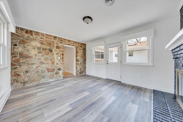 interior space with visible vents, baseboards, ornamental molding, wood finished floors, and a glass covered fireplace