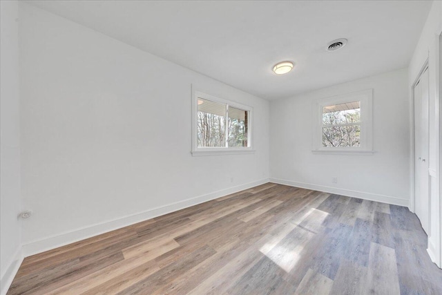 unfurnished bedroom featuring light wood finished floors, multiple windows, baseboards, and a closet