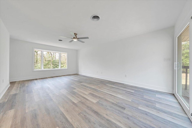 empty room with light wood-style flooring, a ceiling fan, visible vents, and a wealth of natural light